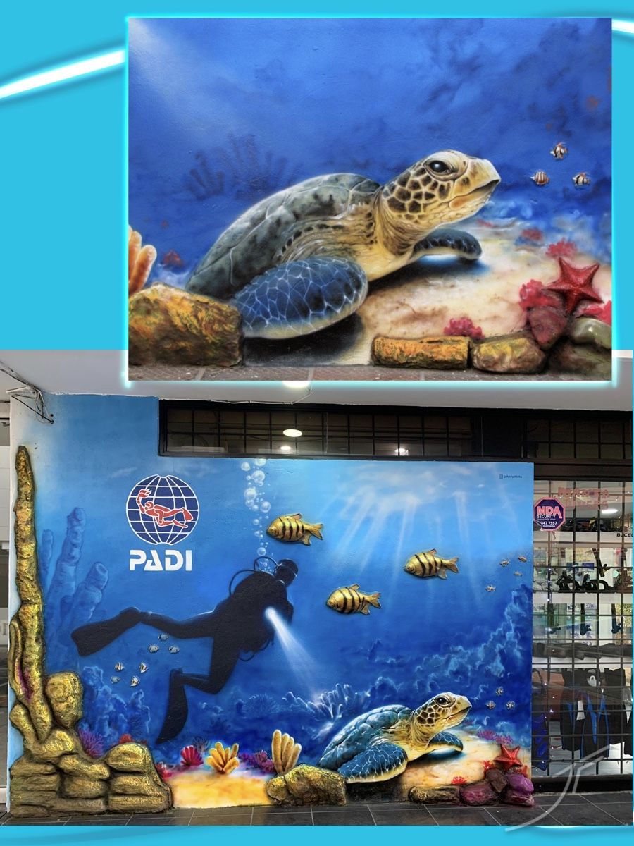 Mural de fondo marino con un buzo, peces y una tortuga, con rocas y coral en relieve junto a una tienda