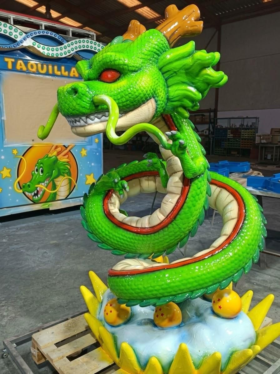 Figura en fibra de vidrio de un dragón verde enroscado sobre esferas del dragón, en un taller